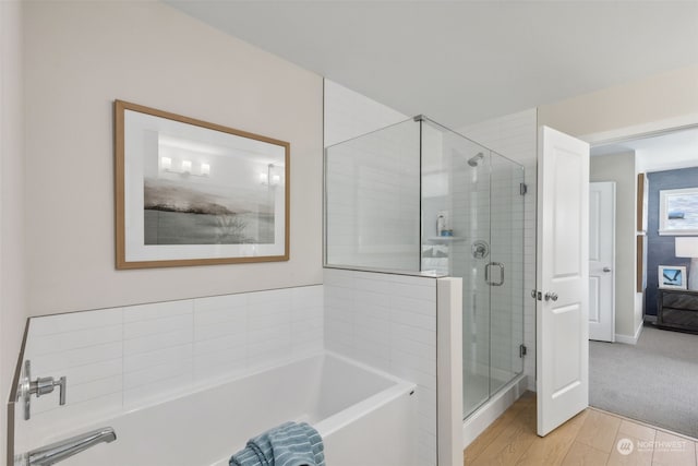 bathroom with shower with separate bathtub and wood-type flooring