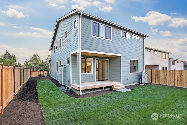 back of property with a deck, cooling unit, and a lawn