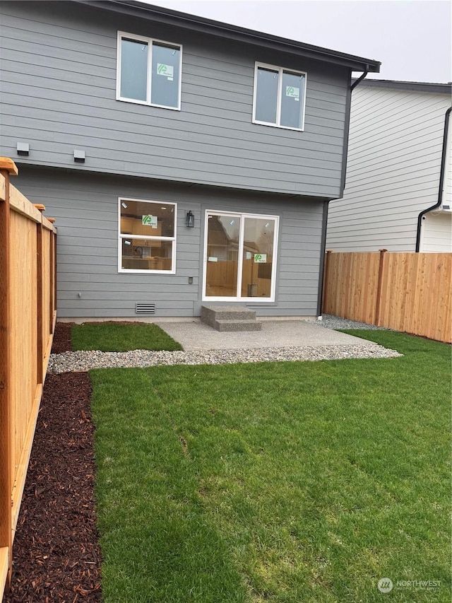 back of house with a lawn and a patio