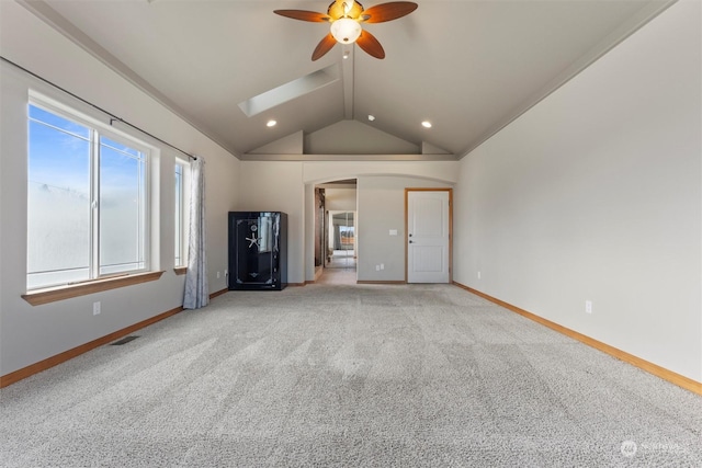 unfurnished living room featuring ceiling fan, light colored carpet, and lofted ceiling with skylight