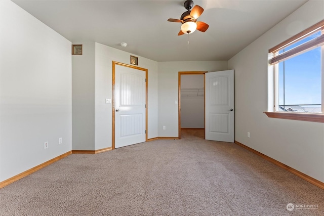 unfurnished bedroom featuring ceiling fan, a closet, a spacious closet, and light carpet