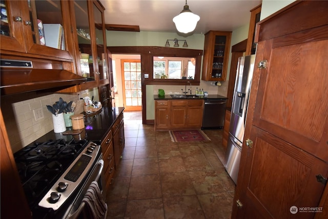 kitchen with appliances with stainless steel finishes, hanging light fixtures, decorative backsplash, sink, and extractor fan