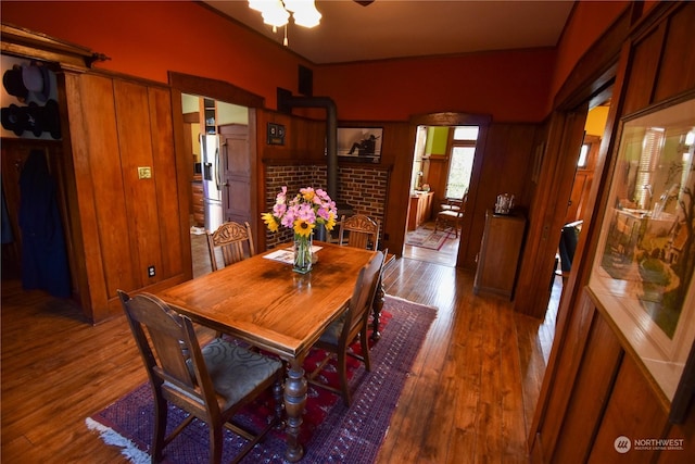 dining area with ceiling fan, a wood stove, and wood-type flooring