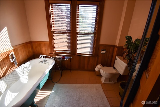 bathroom featuring toilet, tile patterned floors, and a bath