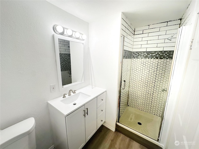 bathroom with toilet, walk in shower, vanity, and hardwood / wood-style flooring