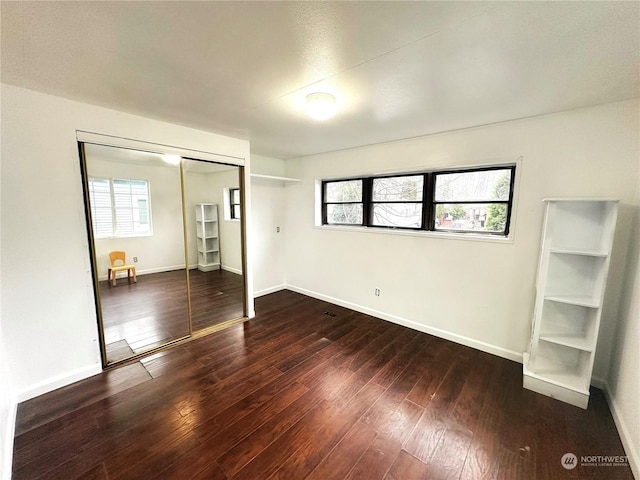 unfurnished bedroom featuring a closet and dark hardwood / wood-style flooring