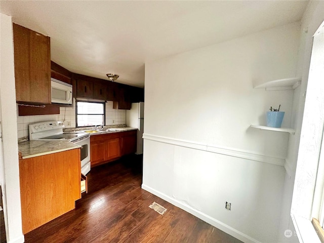 kitchen with white appliances, backsplash, and dark hardwood / wood-style floors