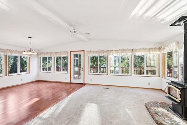 unfurnished sunroom featuring ceiling fan with notable chandelier, lofted ceiling with beams, and a wood stove