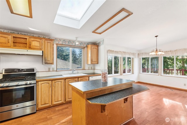 kitchen with a kitchen island, hanging light fixtures, white dishwasher, stainless steel range with gas stovetop, and light hardwood / wood-style flooring