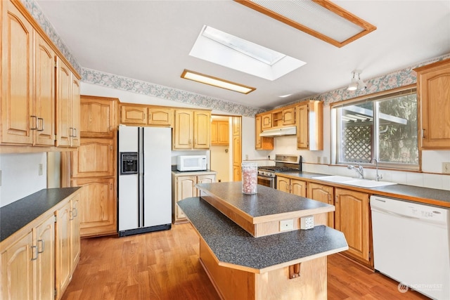 kitchen featuring white appliances, a center island, light hardwood / wood-style flooring, and a skylight