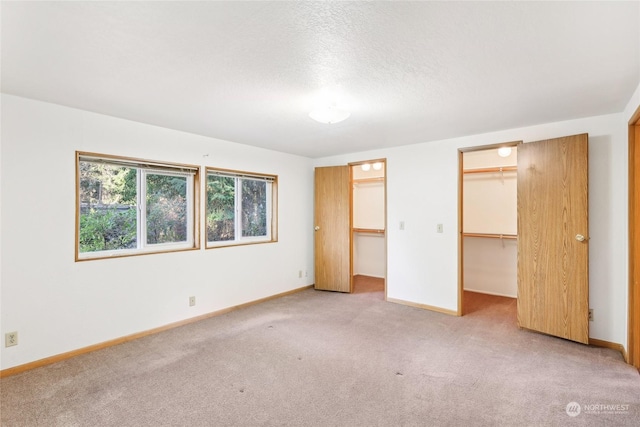 unfurnished bedroom featuring carpet flooring, a spacious closet, and a closet