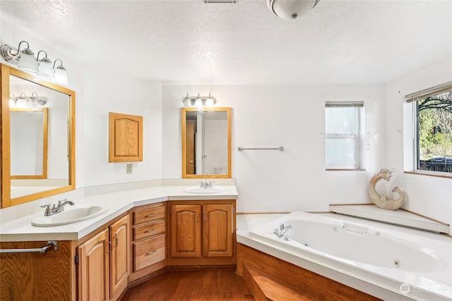 bathroom featuring hardwood / wood-style flooring, vanity, a textured ceiling, and a tub