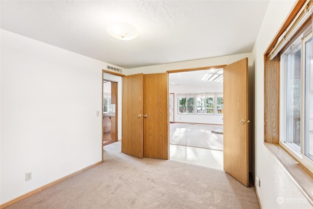 unfurnished bedroom featuring light carpet and a textured ceiling