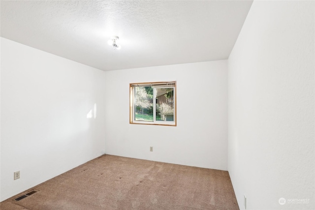 empty room with carpet floors and a textured ceiling