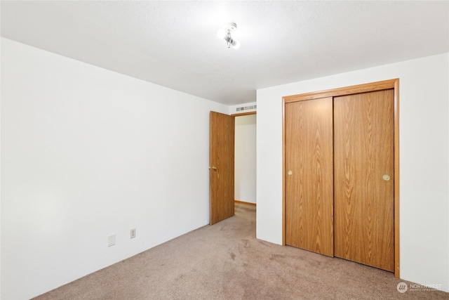 unfurnished bedroom with light carpet and a closet