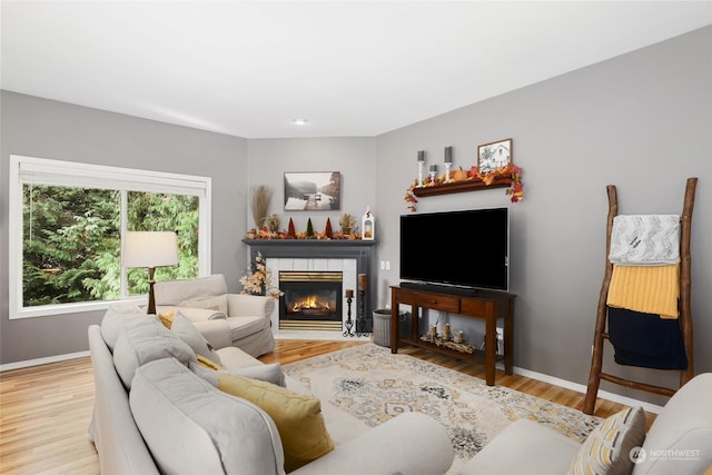 living room with a tile fireplace and light wood-type flooring