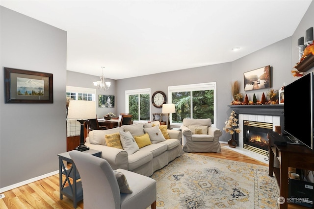 living room with a fireplace, a chandelier, and light hardwood / wood-style flooring