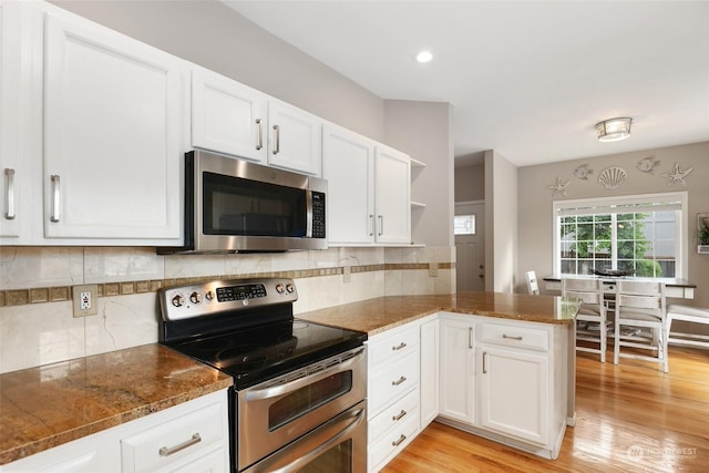 kitchen featuring white cabinetry, appliances with stainless steel finishes, light hardwood / wood-style flooring, and kitchen peninsula