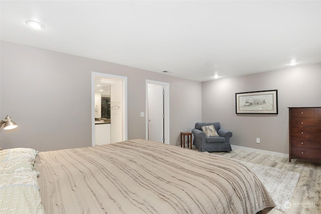 bedroom featuring ensuite bathroom and light hardwood / wood-style floors