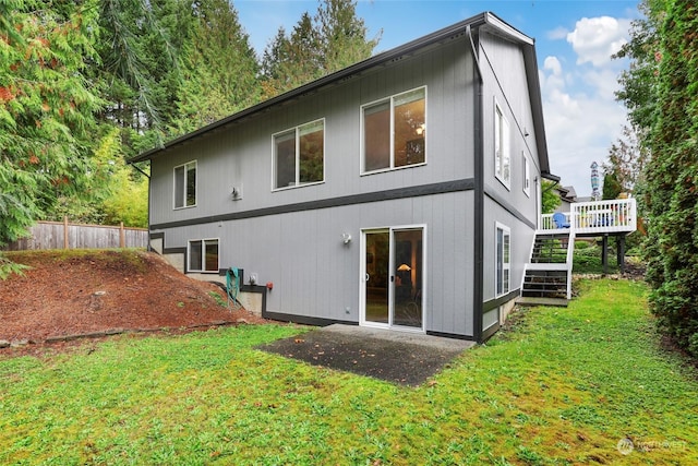 back of property with a wooden deck and a yard