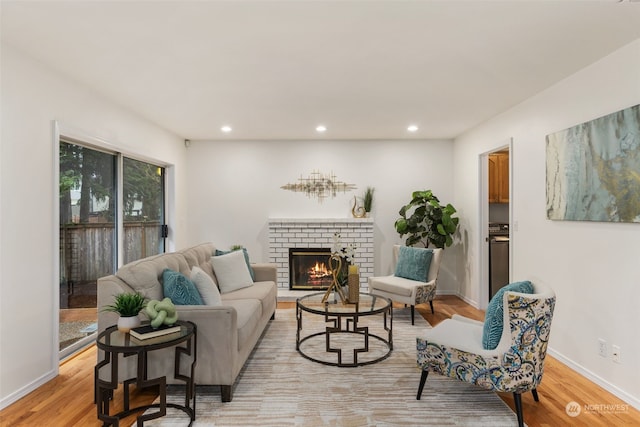 living room featuring a brick fireplace and light wood-type flooring