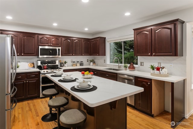 kitchen with sink, a kitchen breakfast bar, a center island, and appliances with stainless steel finishes