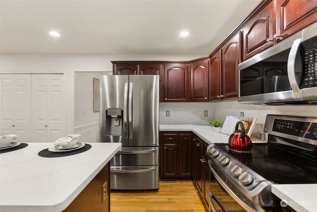 kitchen with stainless steel appliances, light hardwood / wood-style floors, and tasteful backsplash