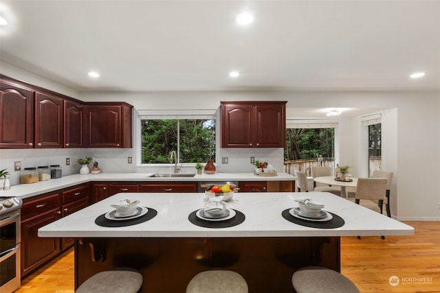 kitchen featuring sink, a kitchen breakfast bar, light hardwood / wood-style floors, and a center island