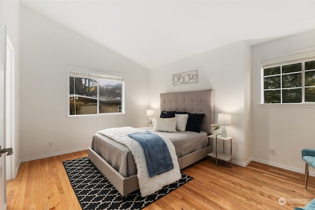 bedroom with hardwood / wood-style floors, vaulted ceiling, and multiple windows