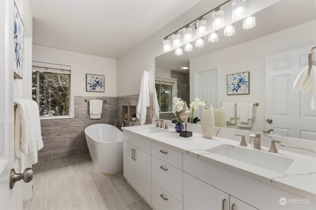 bathroom featuring vanity, tile walls, and a tub to relax in