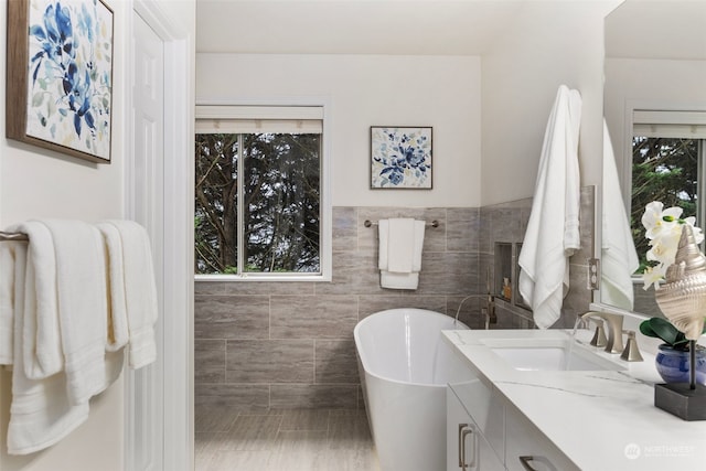 bathroom featuring tile patterned floors, vanity, tile walls, and a tub