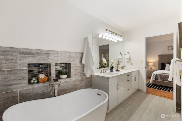 bathroom featuring hardwood / wood-style floors, vanity, tile walls, and a tub to relax in