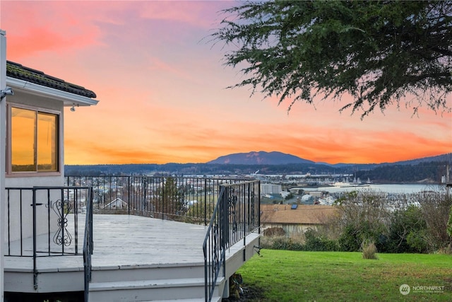 deck at dusk with a yard and a mountain view