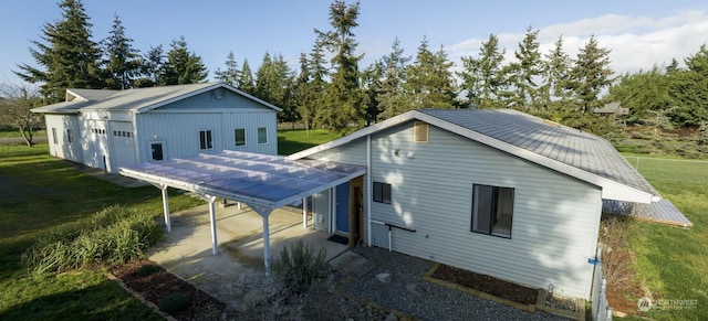 rear view of property with a garage, a lawn, and a carport