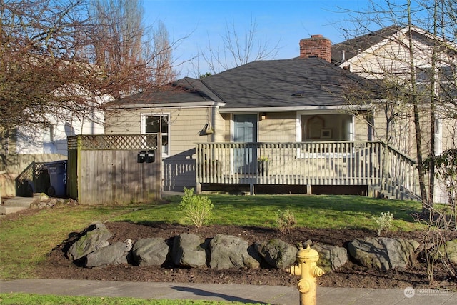 rear view of house with a lawn and a wooden deck