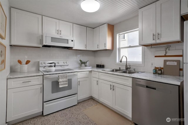 kitchen featuring white appliances, light tile patterned floors, backsplash, white cabinets, and sink