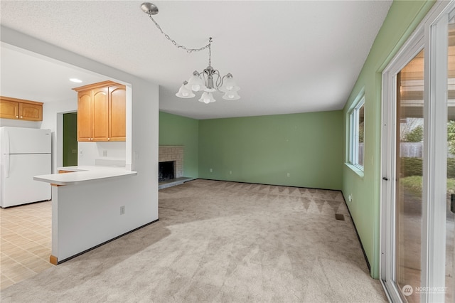 kitchen with a brick fireplace, a chandelier, light carpet, and white fridge