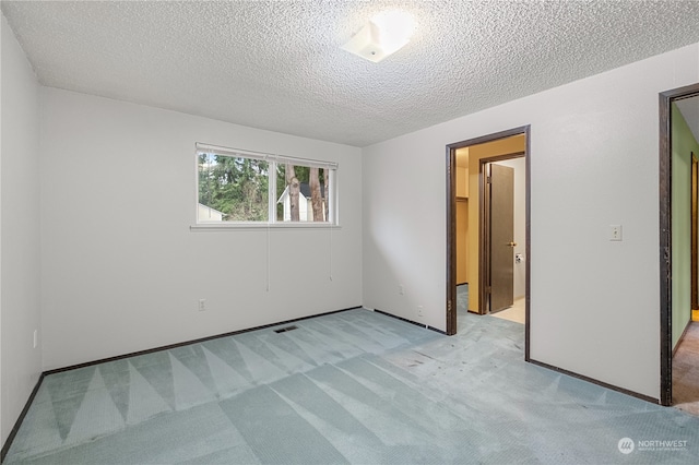 unfurnished bedroom with light colored carpet and a textured ceiling