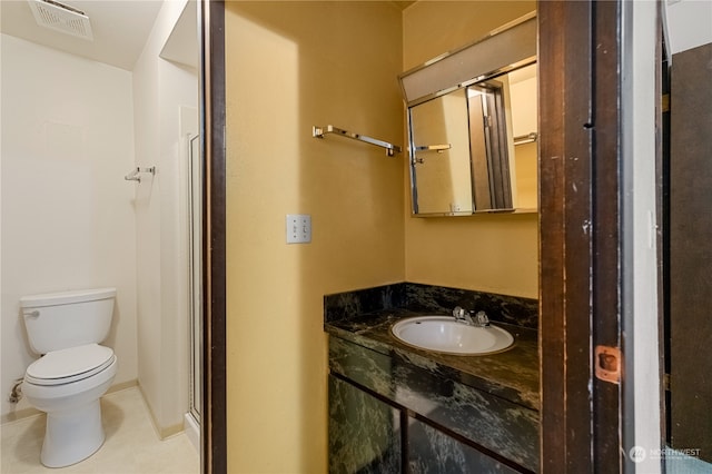 bathroom featuring toilet, vanity, an enclosed shower, and tile patterned flooring