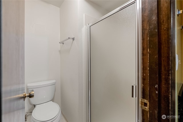 bathroom featuring toilet and a shower with door