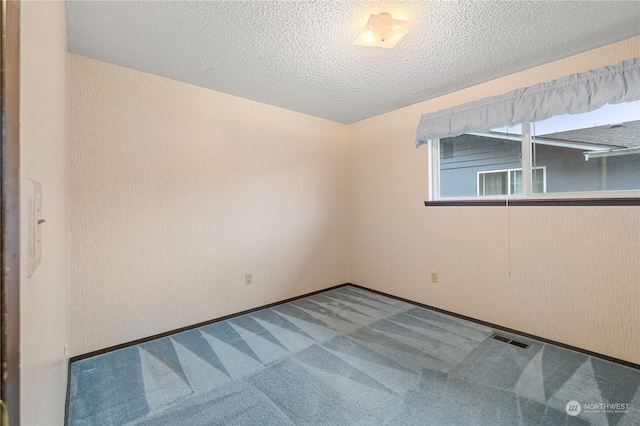 carpeted empty room with a textured ceiling