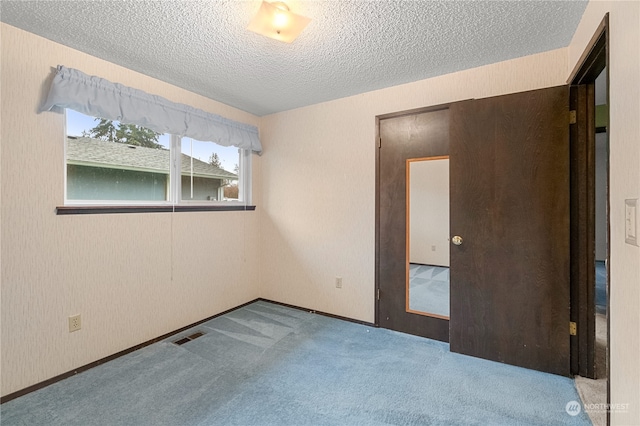 carpeted spare room with a textured ceiling