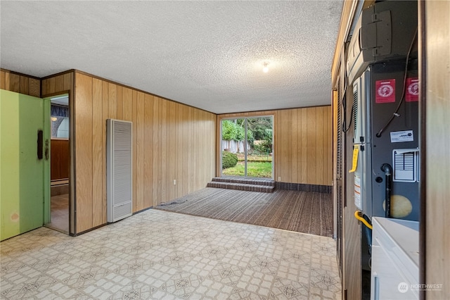 interior space featuring a textured ceiling and wood walls