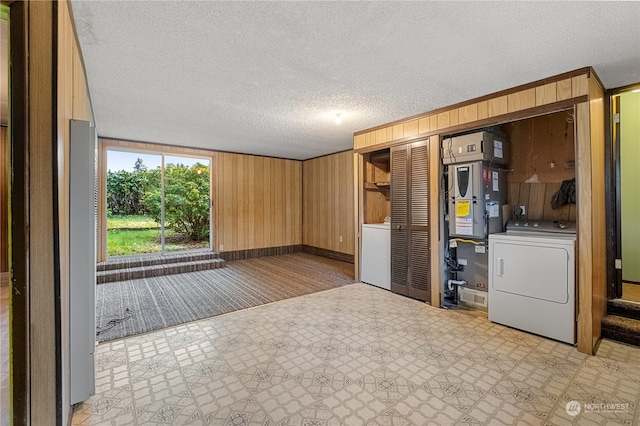 interior space with a textured ceiling, heating unit, wood walls, and washer / clothes dryer