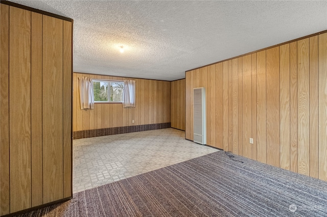 empty room with a textured ceiling and wooden walls