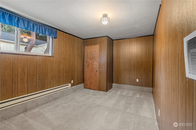 interior space featuring baseboard heating, light carpet, and wooden walls