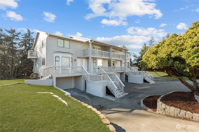 view of front of property featuring a garage, a balcony, and a front lawn