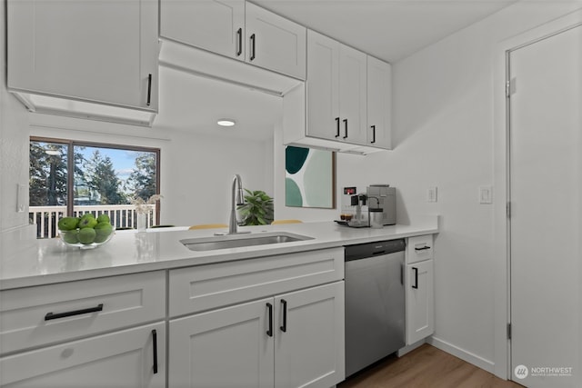 kitchen with sink, white cabinetry, light hardwood / wood-style flooring, and stainless steel dishwasher