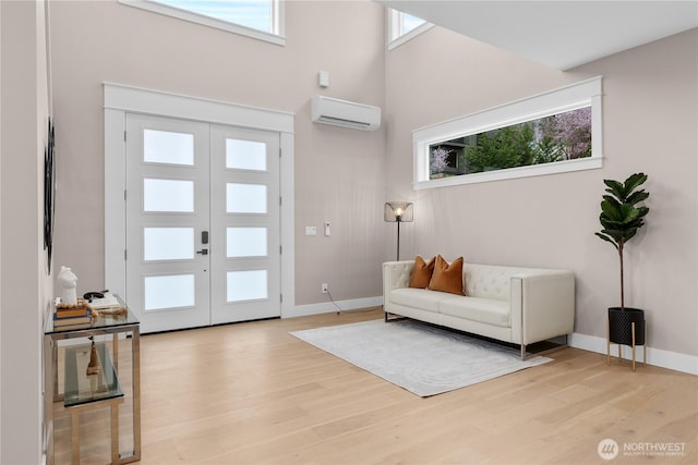 entryway with baseboards, french doors, a wall mounted air conditioner, and light wood-style floors