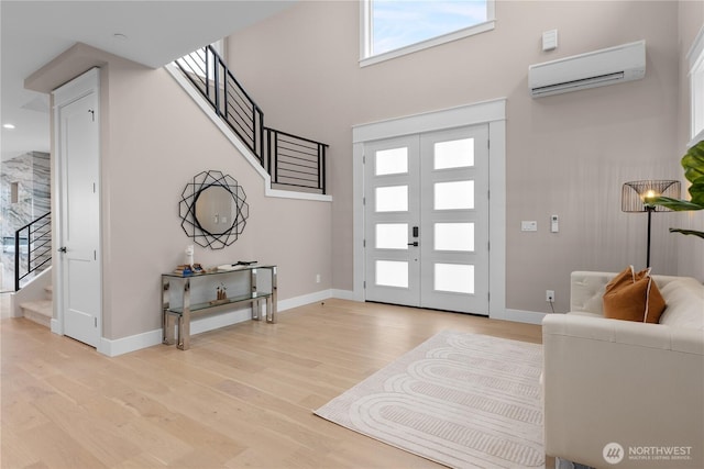 foyer entrance featuring a wall mounted air conditioner, baseboards, light wood-style floors, and stairs